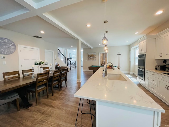 kitchen featuring wood-type flooring, sink, a large island, and white cabinets