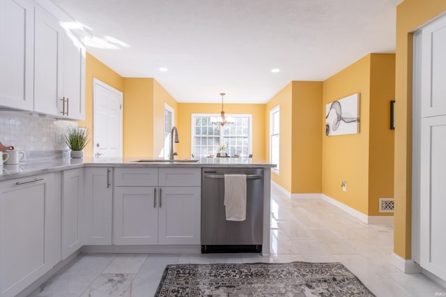 kitchen featuring white cabinets, pendant lighting, sink, tasteful backsplash, and stainless steel dishwasher