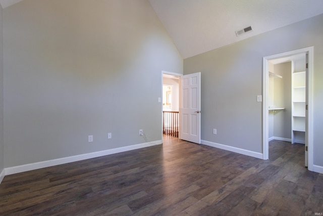 unfurnished bedroom featuring a closet, dark hardwood / wood-style floors, a walk in closet, and high vaulted ceiling