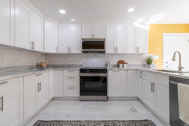 kitchen with light stone counters, tasteful backsplash, sink, white cabinets, and appliances with stainless steel finishes