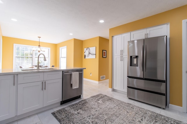 kitchen featuring pendant lighting, stainless steel appliances, white cabinetry, and sink