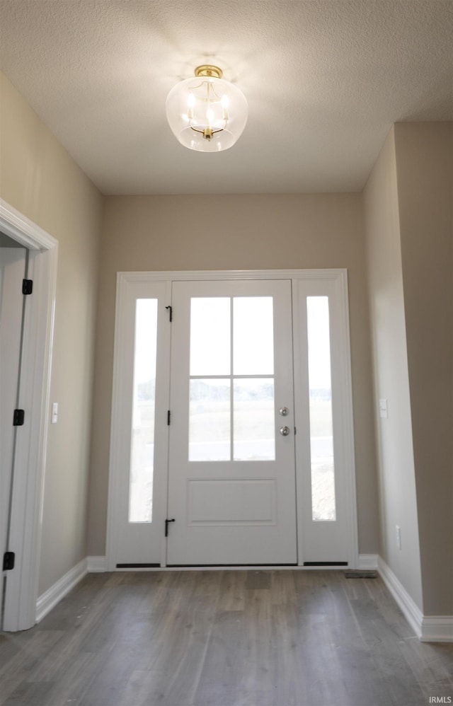 doorway to outside featuring a textured ceiling and hardwood / wood-style floors