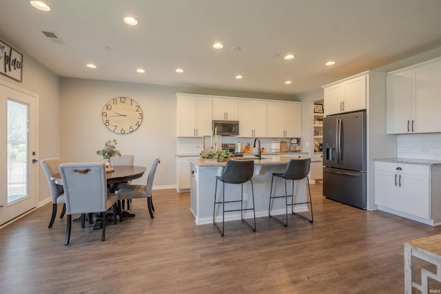 kitchen with stainless steel appliances, light stone counters, and white cabinets