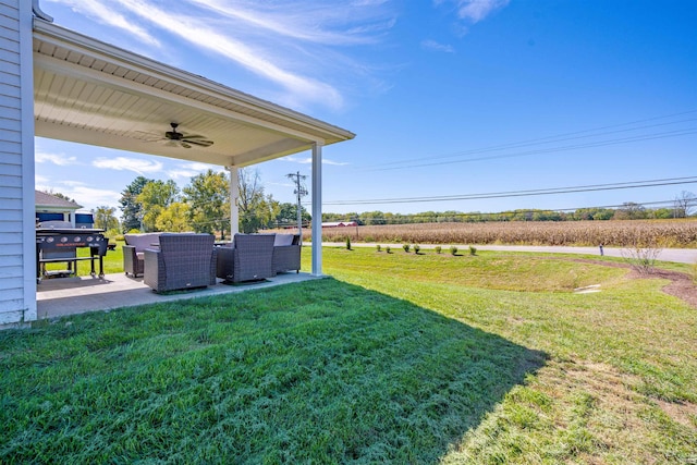 view of yard with a patio, an outdoor living space, ceiling fan, and a rural view