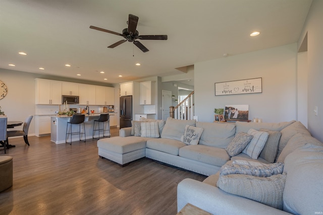 living room featuring ceiling fan, sink, and dark wood-type flooring