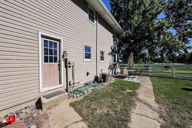 view of side of home with central AC unit, a lawn, and a patio