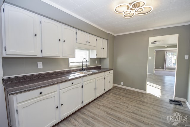 kitchen featuring light wood-type flooring, a wealth of natural light, sink, and white cabinets