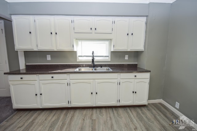 kitchen with light hardwood / wood-style floors, sink, and white cabinetry