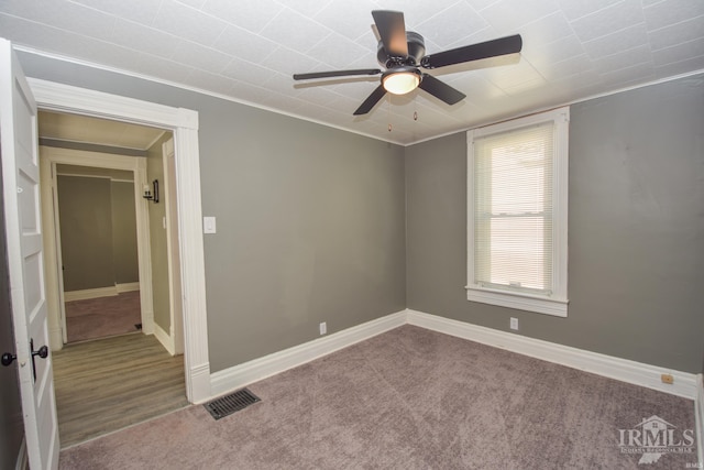 carpeted spare room with ceiling fan and crown molding