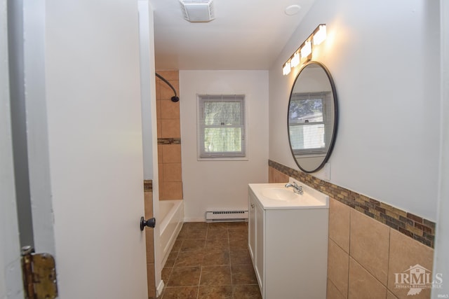 bathroom featuring vanity, baseboard heating, tiled shower / bath combo, and tile patterned flooring