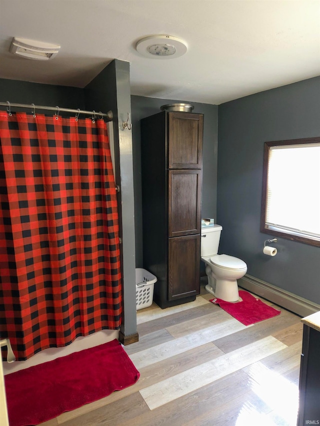 bathroom with hardwood / wood-style floors, baseboard heating, vanity, and toilet