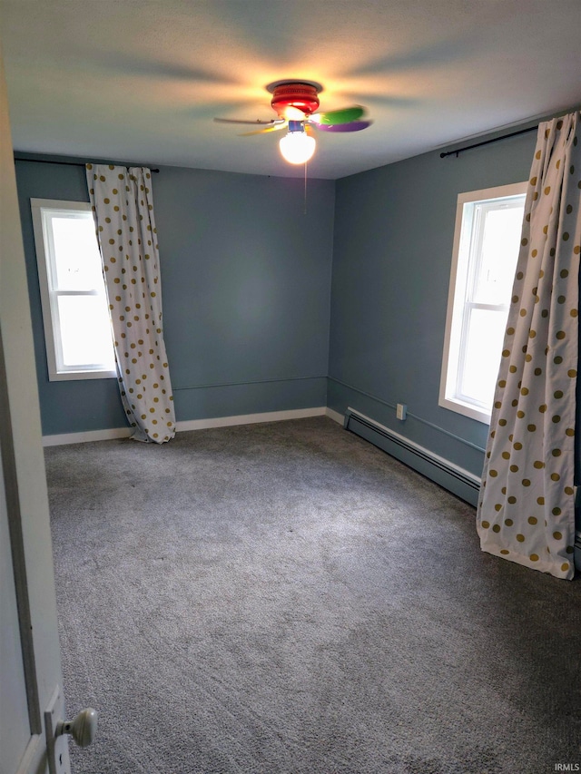 empty room with ceiling fan, carpet, and a baseboard heating unit