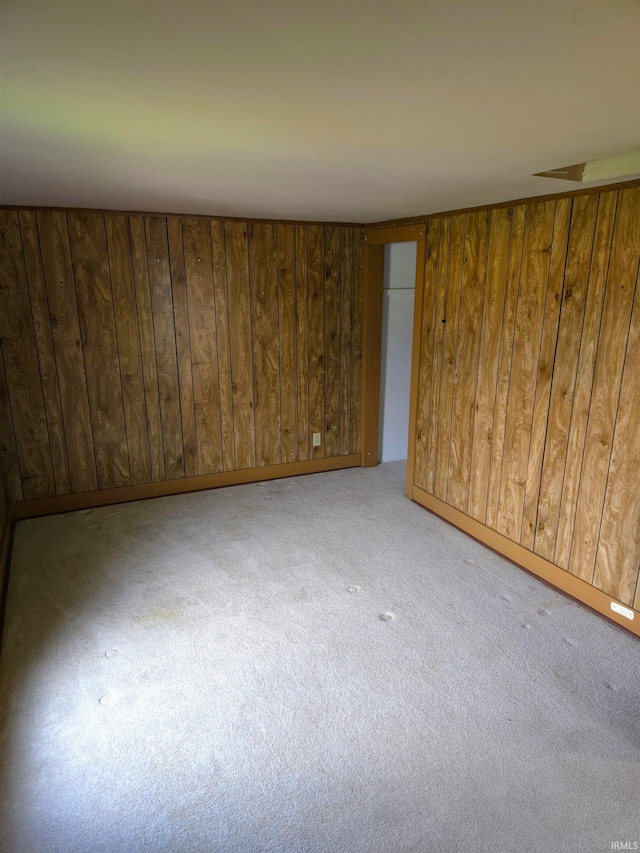 carpeted empty room with wood walls