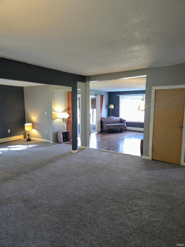 carpeted spare room with a baseboard radiator and a textured ceiling