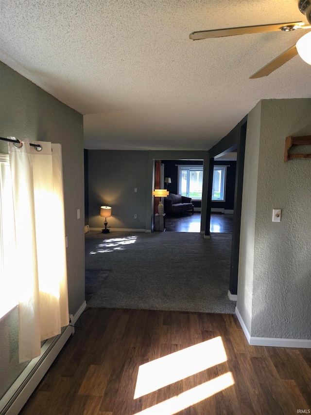 hallway with a textured ceiling, dark hardwood / wood-style flooring, and a baseboard heating unit