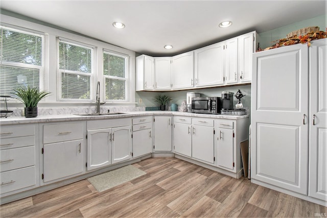 kitchen featuring white cabinetry, light hardwood / wood-style floors, and sink