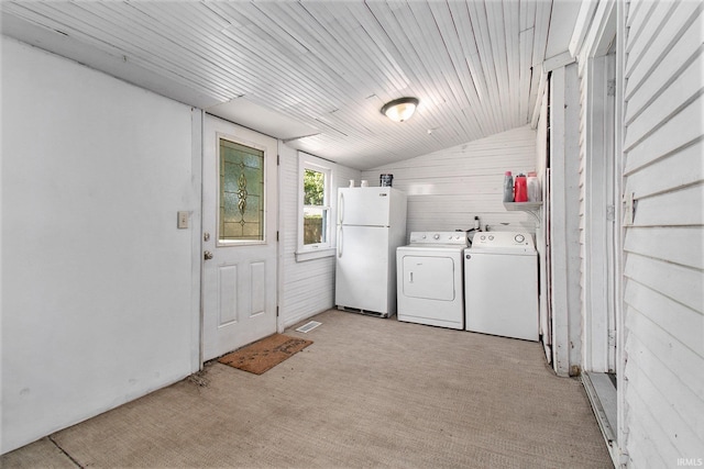 laundry area featuring separate washer and dryer, wooden walls, and light colored carpet