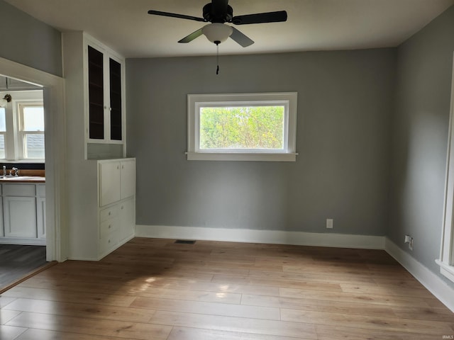 empty room featuring ceiling fan, sink, and light hardwood / wood-style floors