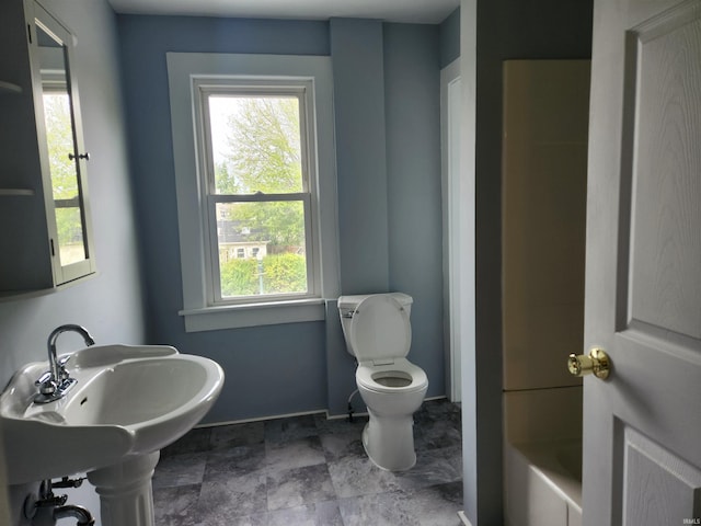 bathroom with a washtub and toilet