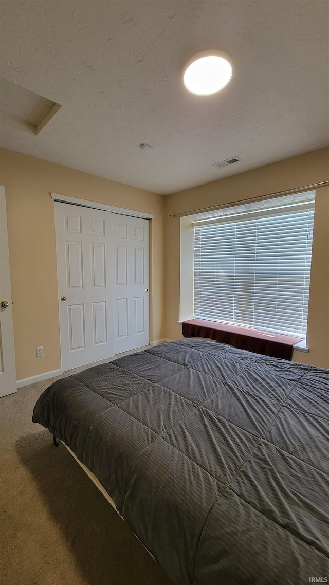 bedroom featuring a textured ceiling, carpet flooring, and a closet