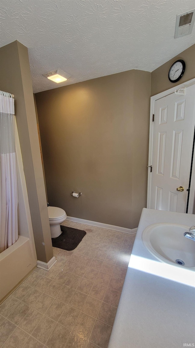 full bathroom with tile patterned floors, a textured ceiling, sink, toilet, and shower / bath combo with shower curtain