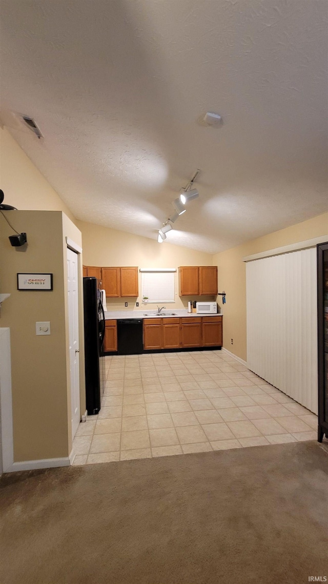 kitchen featuring black appliances, lofted ceiling, track lighting, and light colored carpet