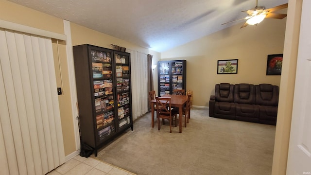 interior space featuring a textured ceiling, light colored carpet, lofted ceiling, and ceiling fan