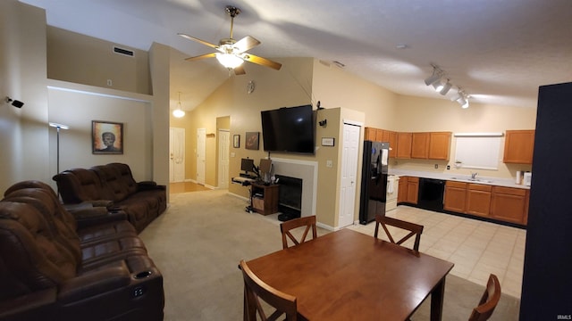 carpeted dining room featuring ceiling fan, rail lighting, sink, and high vaulted ceiling