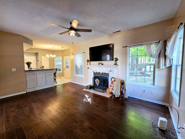 living room with a textured ceiling, ceiling fan with notable chandelier, and dark hardwood / wood-style floors