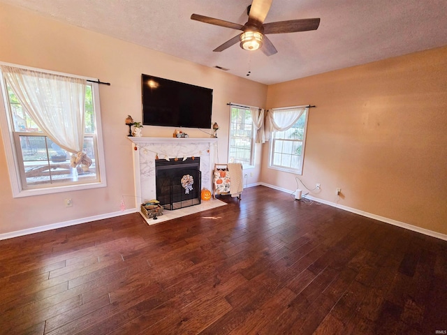 unfurnished living room with ceiling fan, a textured ceiling, a fireplace, and dark wood-type flooring