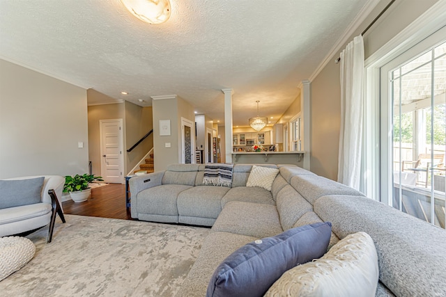 living room with a chandelier, a textured ceiling, hardwood / wood-style flooring, and crown molding