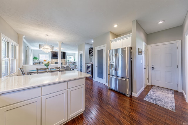 kitchen featuring stainless steel fridge, white cabinetry, dark wood-type flooring, and pendant lighting