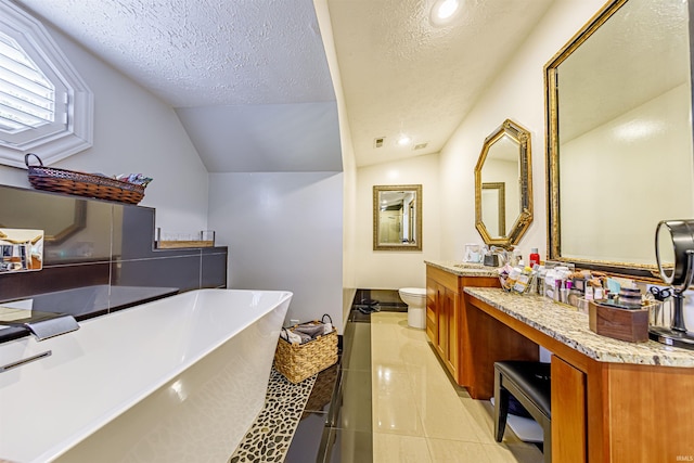 bathroom featuring a textured ceiling, lofted ceiling, vanity, and toilet