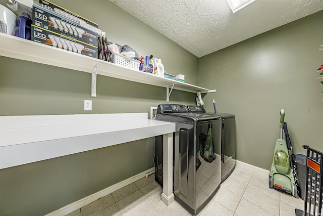 clothes washing area with a textured ceiling, light tile patterned floors, and washing machine and clothes dryer