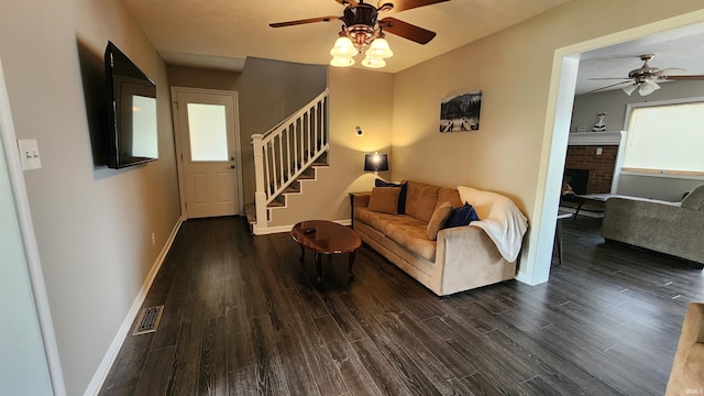 living room with a brick fireplace, ceiling fan, dark wood-type flooring, and a healthy amount of sunlight