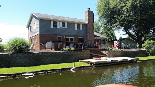 back of property featuring a yard and a deck with water view