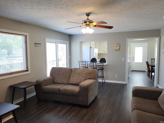 living room featuring ceiling fan, dark wood-type flooring, and a textured ceiling