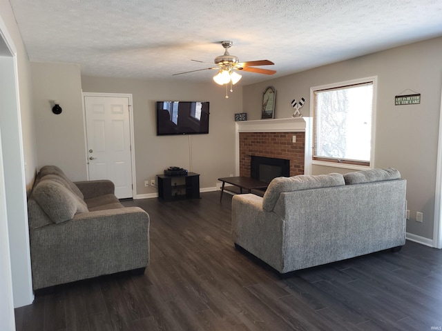 living room featuring a textured ceiling, a fireplace, ceiling fan, and dark wood-type flooring