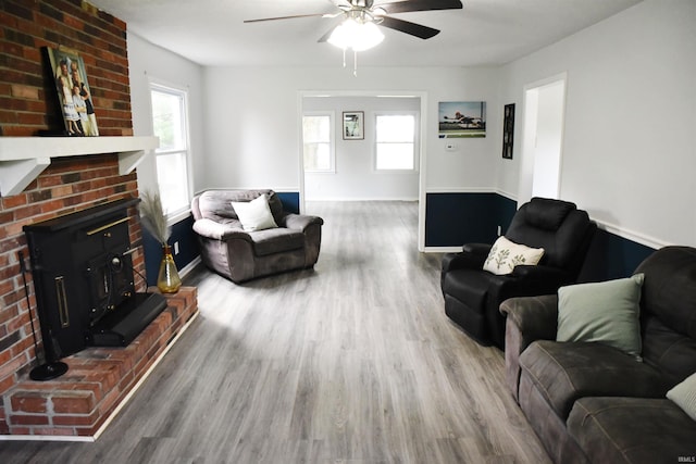 living room with a brick fireplace, ceiling fan, hardwood / wood-style floors, and a wealth of natural light