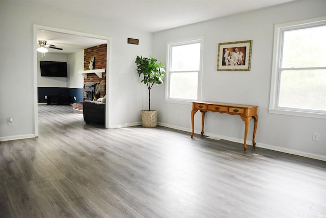 empty room featuring a fireplace, ceiling fan, and hardwood / wood-style flooring