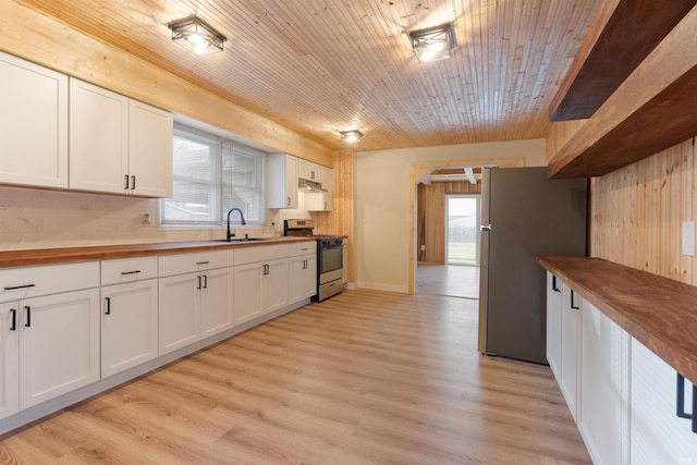 kitchen featuring butcher block countertops, appliances with stainless steel finishes, light hardwood / wood-style floors, and white cabinetry