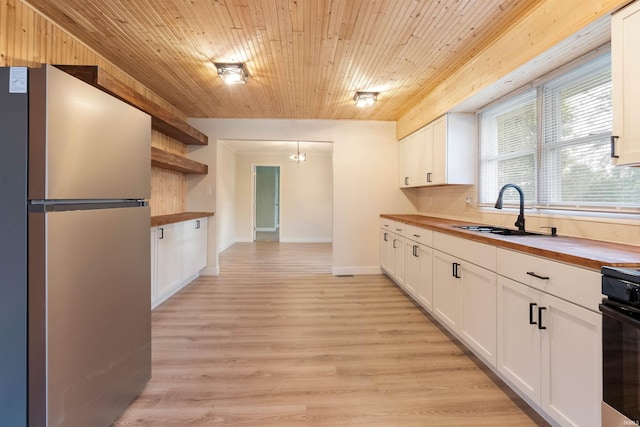 kitchen with white cabinetry, butcher block countertops, and stainless steel fridge