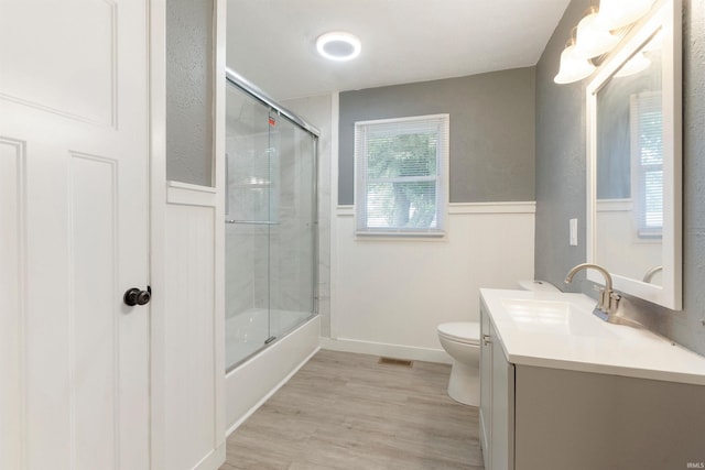 full bathroom featuring wood-type flooring, vanity, toilet, and combined bath / shower with glass door