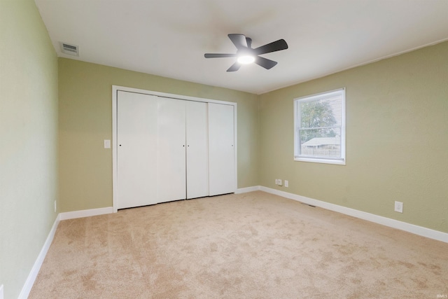 unfurnished bedroom with ceiling fan, light colored carpet, and a closet