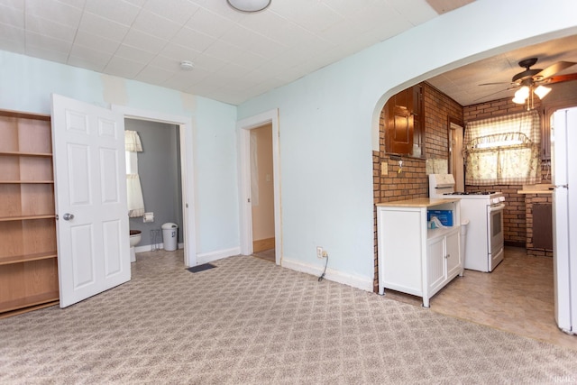 interior space with ceiling fan and brick wall