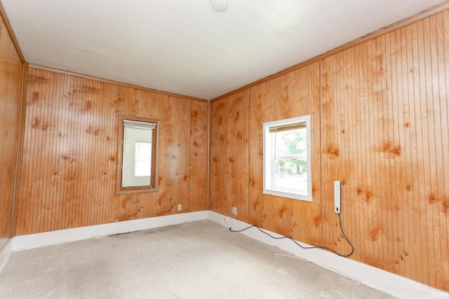 carpeted spare room with crown molding and wood walls