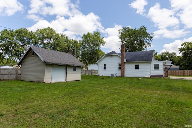 view of yard featuring a garage, central air condition unit, and an outbuilding