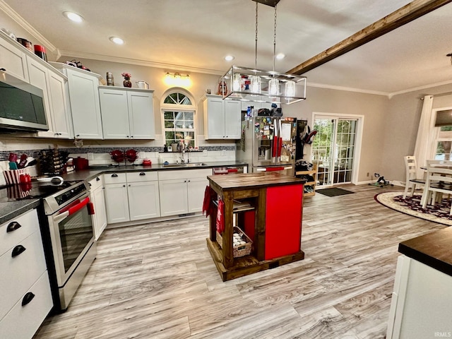 kitchen featuring appliances with stainless steel finishes, tasteful backsplash, light wood-type flooring, decorative light fixtures, and sink