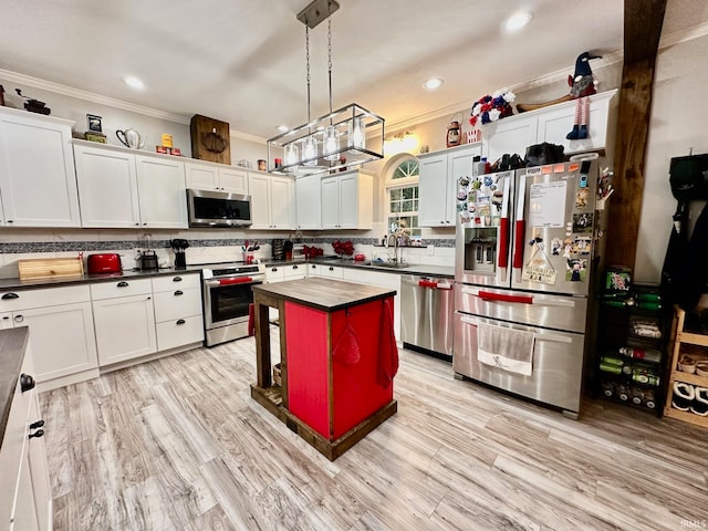 kitchen featuring pendant lighting, appliances with stainless steel finishes, ornamental molding, and a center island