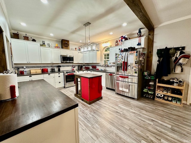 kitchen featuring ornamental molding, a kitchen island, decorative light fixtures, stainless steel appliances, and light wood-type flooring